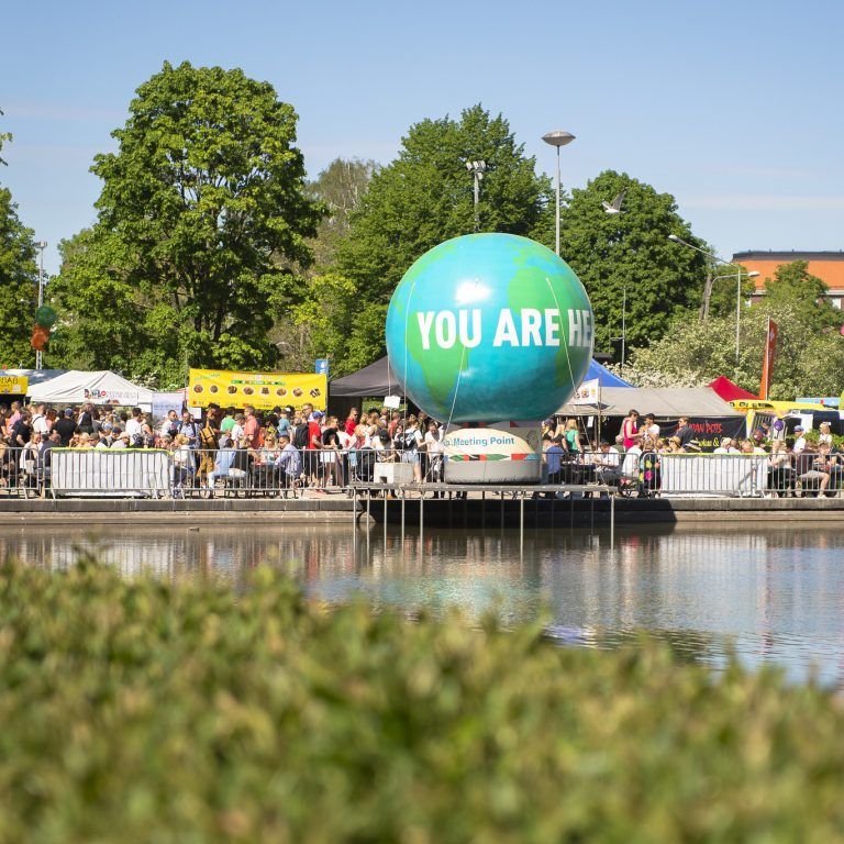 Kuva suuresta maapallokoristeesta Maailma kylässä -festivaalialueella. Pallossa lukee "You are here".