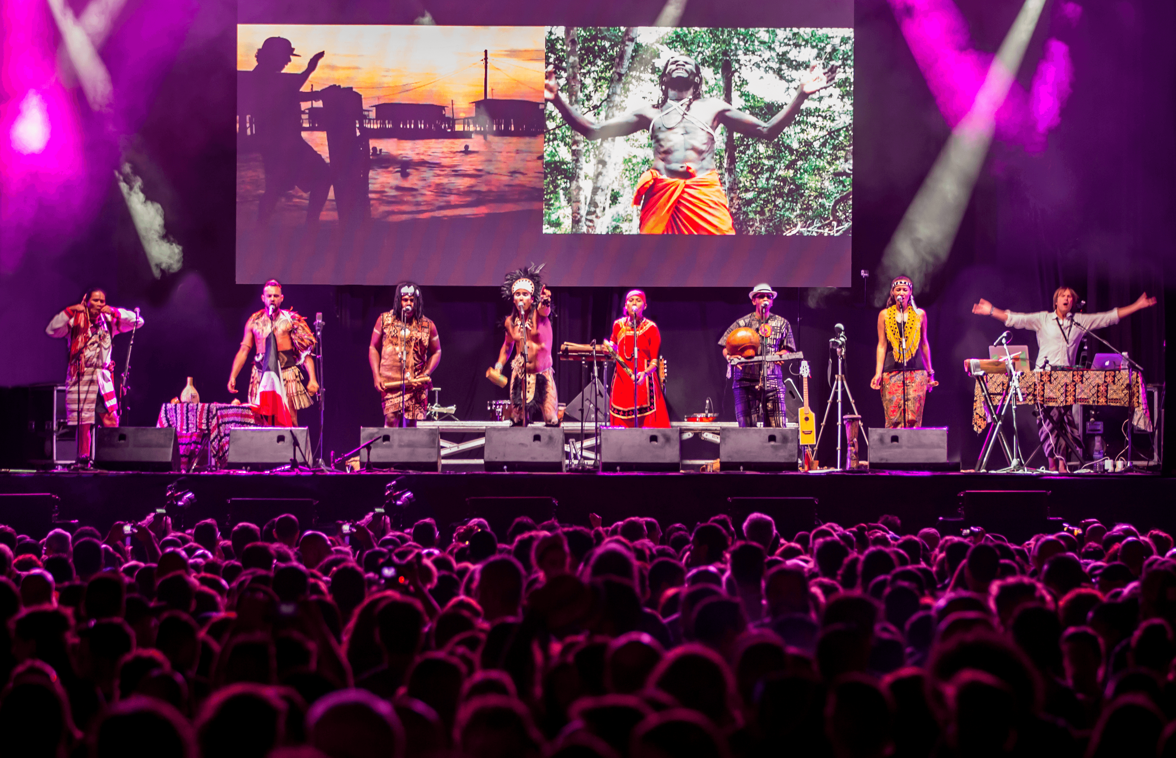 Tyynenmeren alkuperäiskansojen perinteisiin pukuihin pukeutuneita artisteja suurella festivaalilavalla.