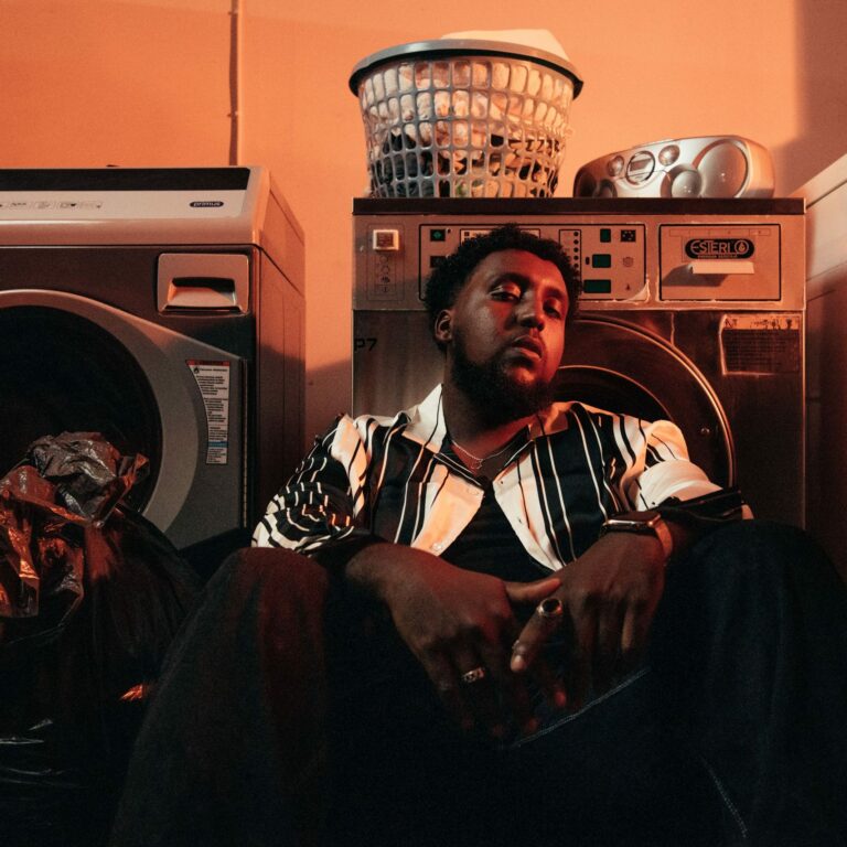 Hassan Maikal sitting on the floor of a laundry room.