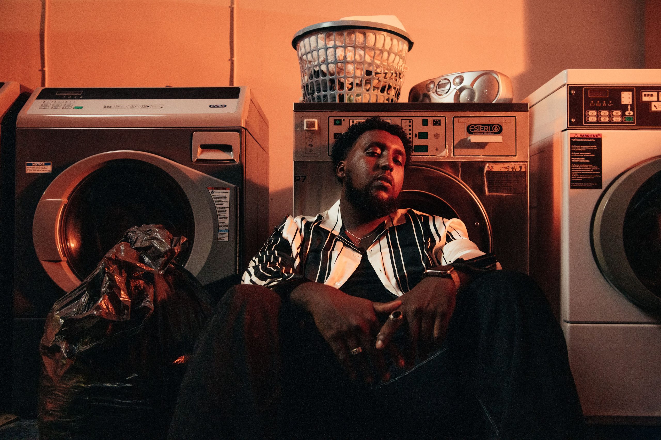 Hassan Maikal sitting on the floor of a laundry room.